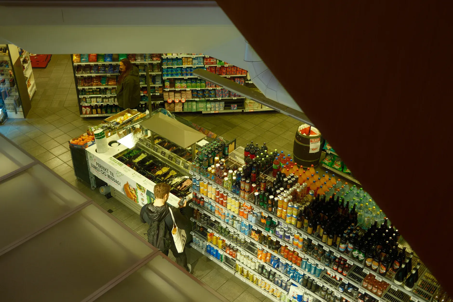 Vista dall'alto di un supermercato, che mostra i clienti mentre curiosano nel reparto bevande.